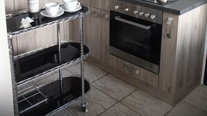 Une cuisine moderne avec un four en acier inoxydable, une lampe noire suspendue et une machine à café posée sur le plan de travail.