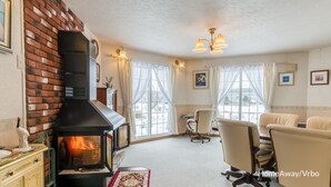 Un salon chaleureux avec une cheminée, des sièges confortables et de grandes fenêtres.