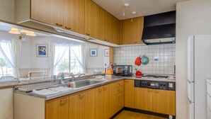 Une cuisine avec des meubles en bois, un évier en acier inoxydable, un four à micro-ondes, une cuisinière et un réfrigérateur.