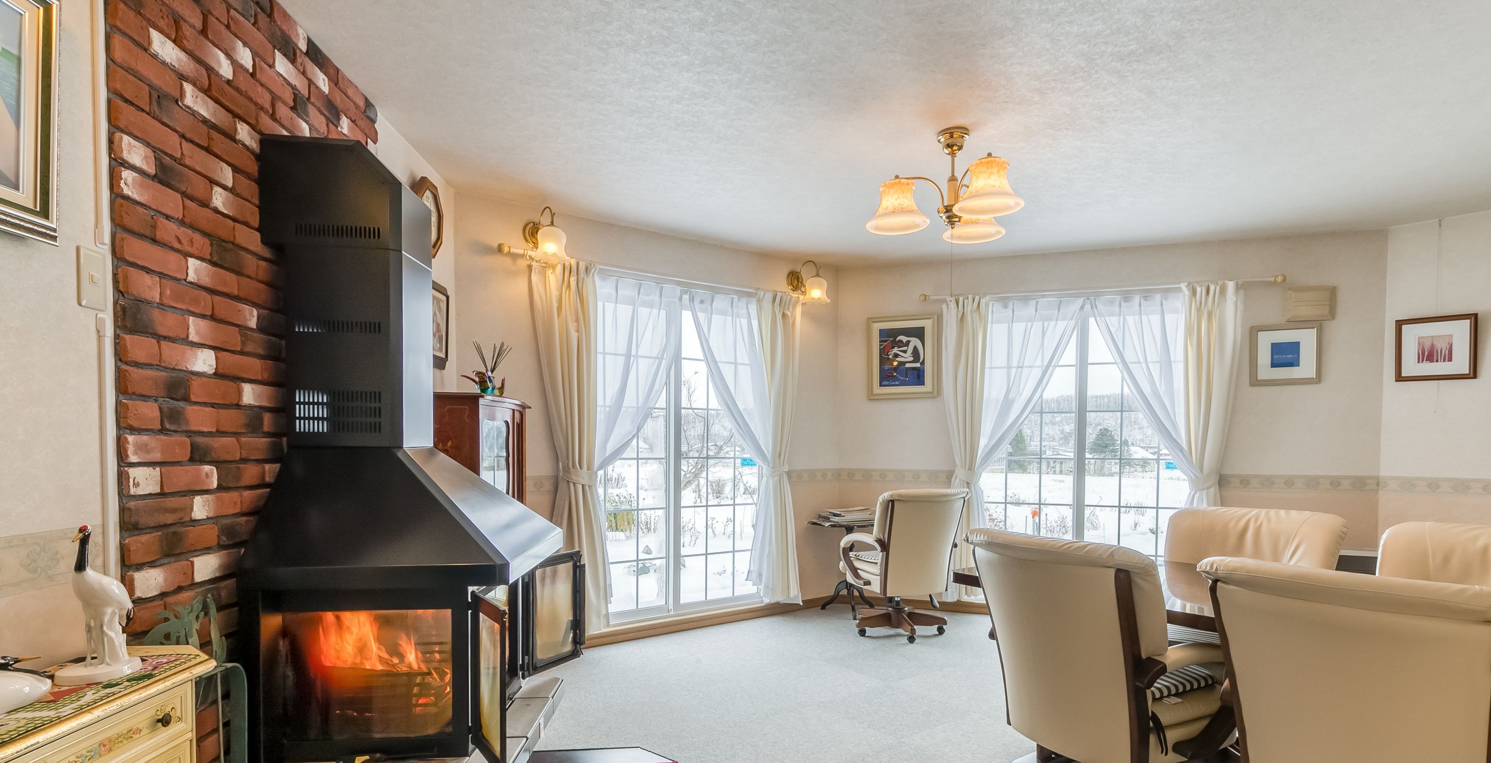 A cozy living room with a fireplace, comfortable seating, and large windows.