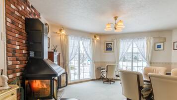 A cozy living room with a fireplace, comfortable seating, and large windows.