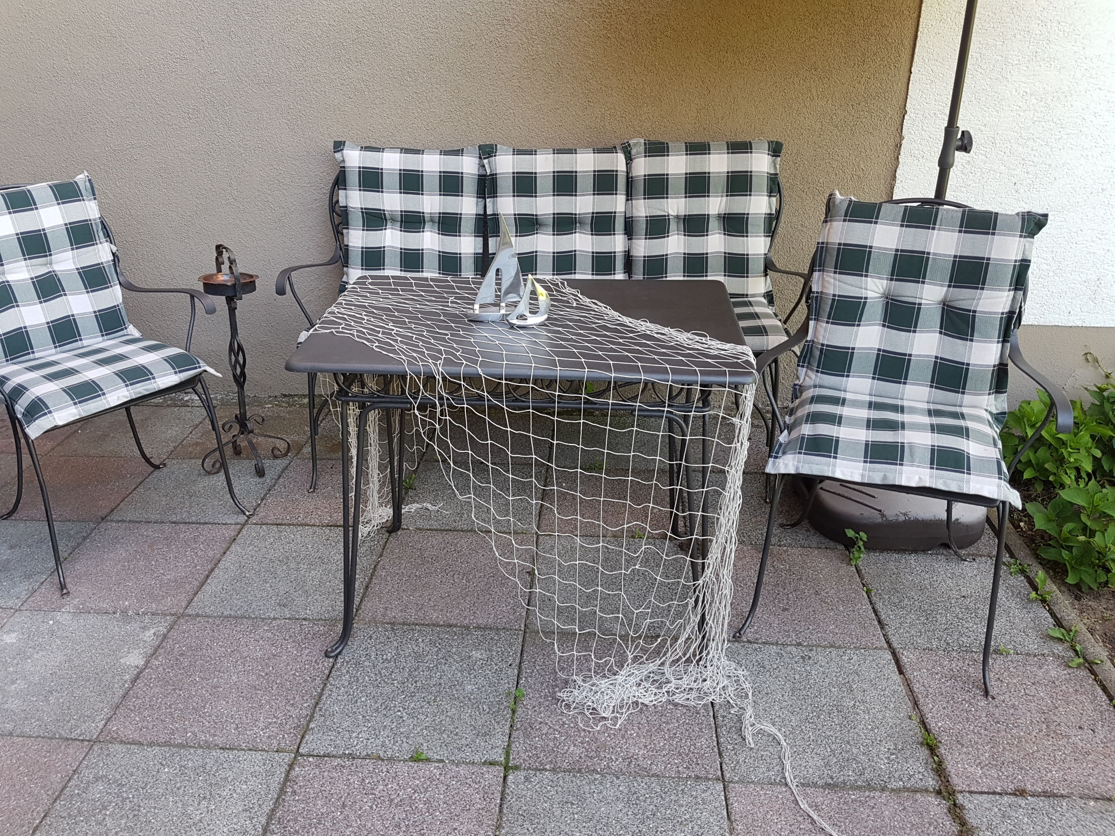 A patio with a table and chairs, covered by a white net.