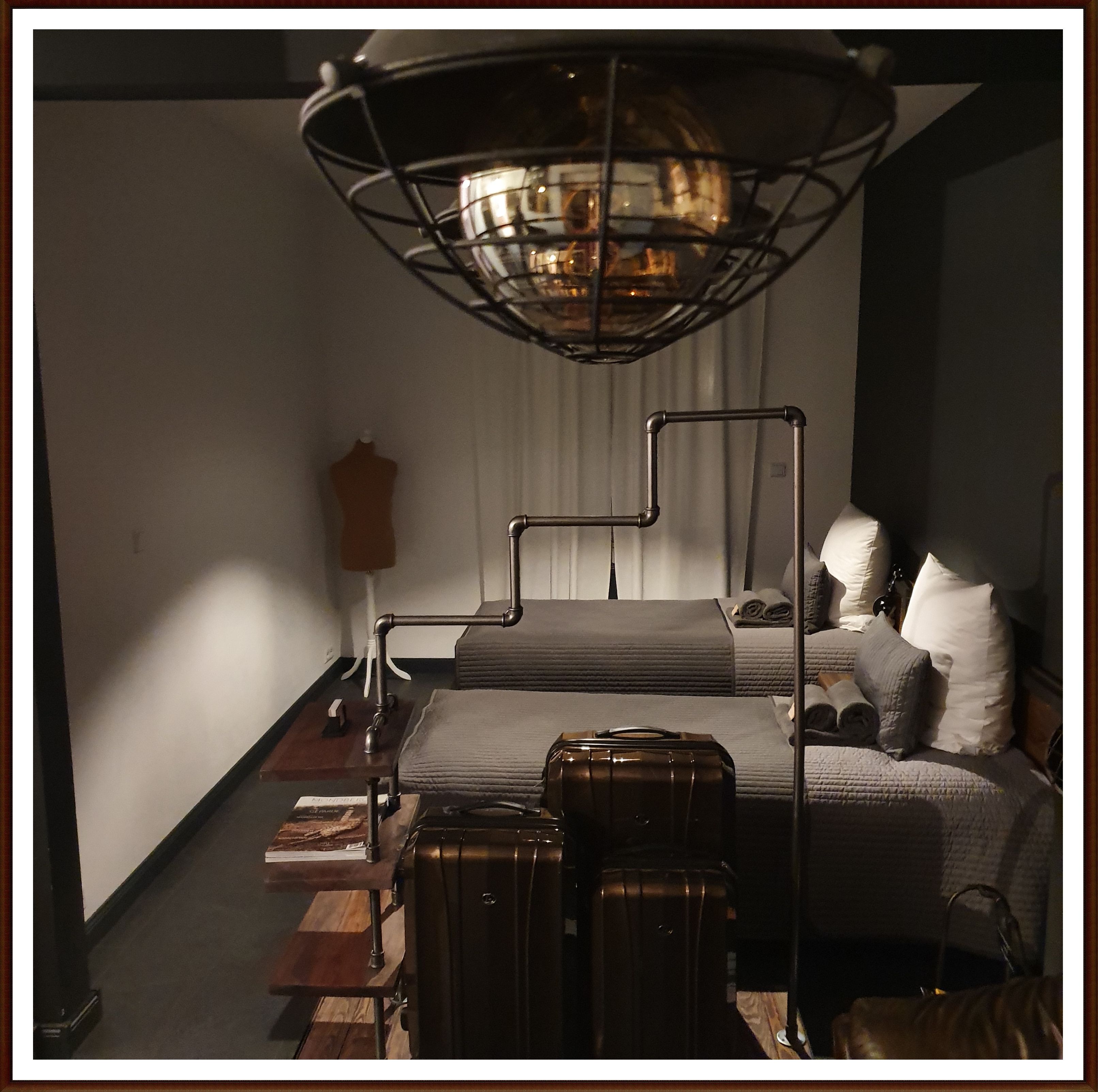 Une chambre à coucher avec un lit, un mannequin, une valise et une lampe.