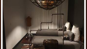 Une chambre à coucher avec un lit, un mannequin, une valise et une lampe.