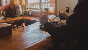 A wooden interior with a large window, a bar area, and a person wearing a cowboy hat. - Lava Mountain Lodge (Dubois)