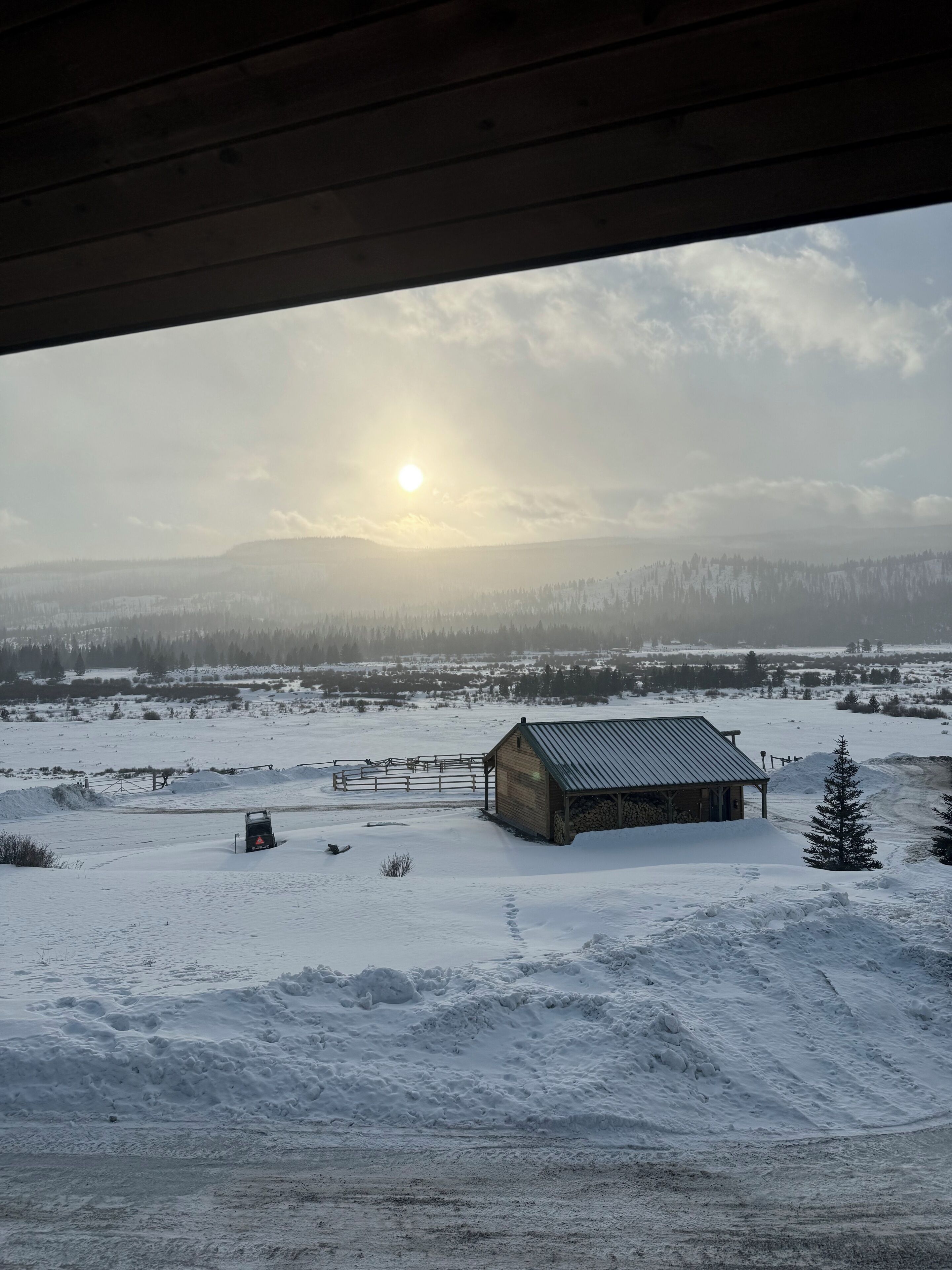 A snowy landscape with a wooden cabin, a tractor, and a clear sky.