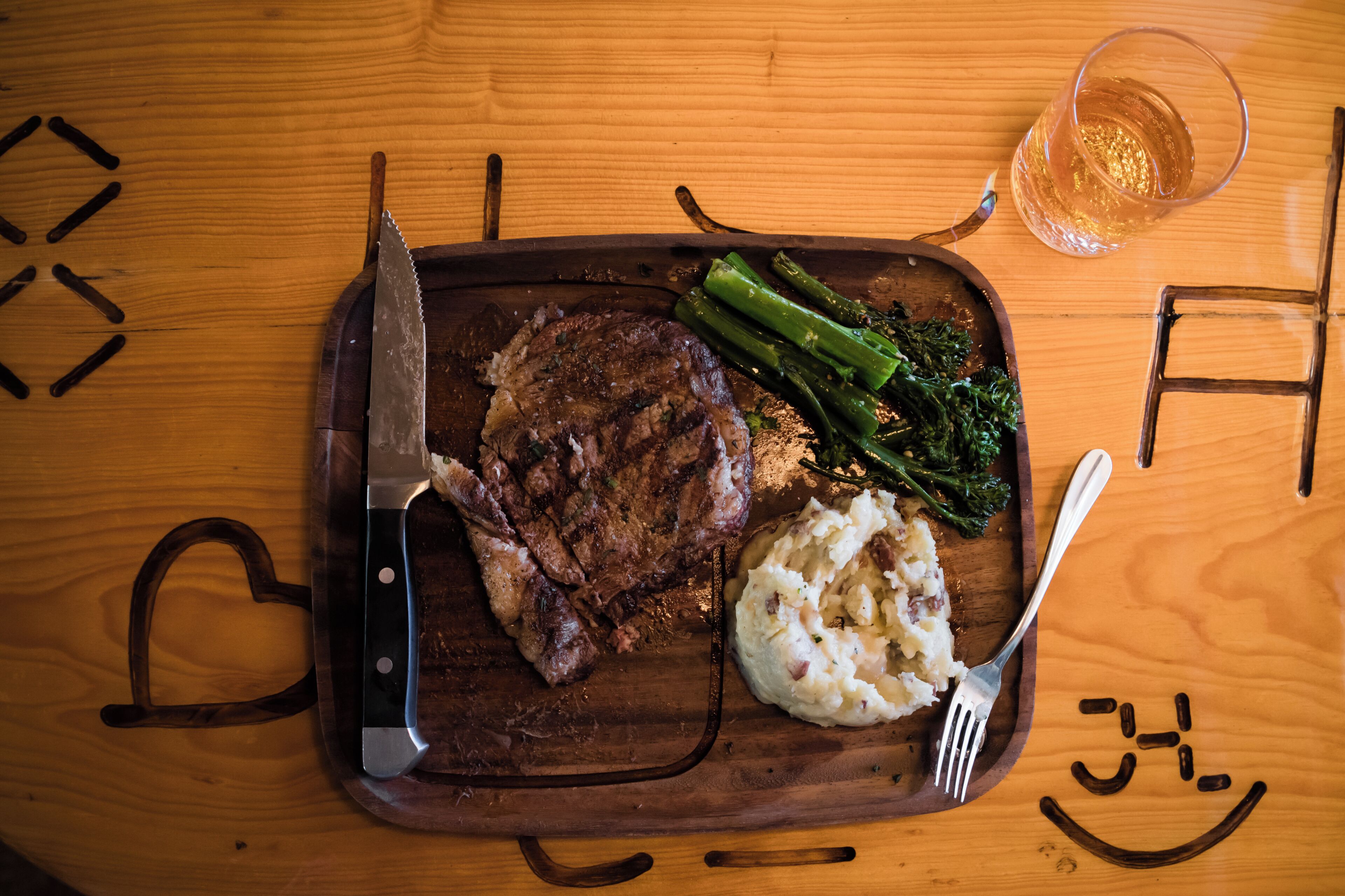 Ein Holztisch mit einem Steak, Spargel und Kartoffelpüree.