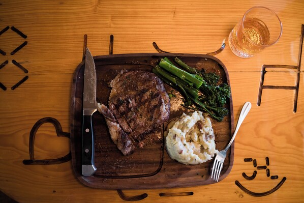 A wooden table with a steak, asparagus, and mashed potatoes. - Lava Mountain Lodge (Dubois)