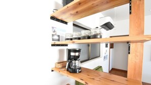 Une cuisine avec des étagères en bois, une machine à café et des bocaux.
