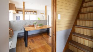 Une cuisine moderne avec un banc en bois, une table à manger et un escalier.