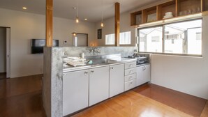 Une cuisine moderne dotée d’un îlot central, de poutres en bois et d’une grande fenêtre qui laisse entrer la lumière naturelle.