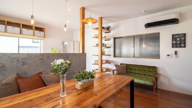 Un intérieur moderne avec une table à manger en bois, un canapé vert et une grande fenêtre.