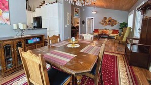 A spacious dining area with a wooden table, chairs, and a chandelier.