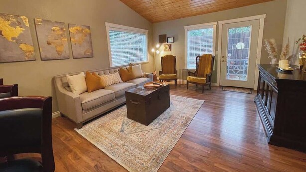 A spacious living room with a wooden ceiling, a sofa, a coffee table, and a dining area with chairs.