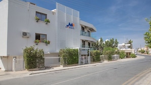 Un edificio moderno con fachada plana, un logotipo destacado y una entrada protegida por un portón.