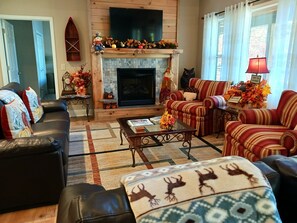 A cozy living room with a fireplace, striped armchairs, a sofa, and a coffee table. - LAKEFRONT 4/3.5, Private Dock, Pool Table, Lakeside Firepit, Kayaks, Paddleboat (Young Harris)