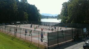 Una cancha de tenis al aire libre rodeada de árboles y un lago.
