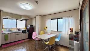 A compact kitchen with a dining area, featuring a sink, microwave, refrigerator, and a window with curtains. - N ° 5  CONDOMINIUM - Second Floor Corner Apartment; 2 BedRoom Japanese Style (Osaka-shi)