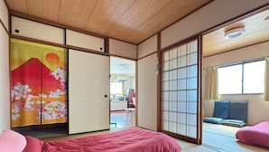 A traditional Japanese-style room with tatami flooring, a sliding shoji screen, and a bed with pink bedding. - N ° 5  CONDOMINIUM - Second Floor Corner Apartment; 2 BedRoom Japanese Style (Osaka-shi)