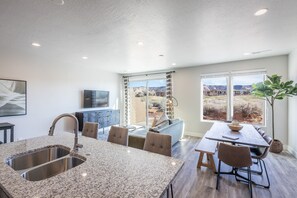 A modern kitchen with granite countertops, a built-in sink, and a dining area with a large table and chairs. - 4BR on the 18th Green - Desert & Mountain Views (St. George)