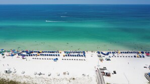 Une plage aux eaux turquoise et limpides, dotée de nombreux parasols et de chaises de plage.