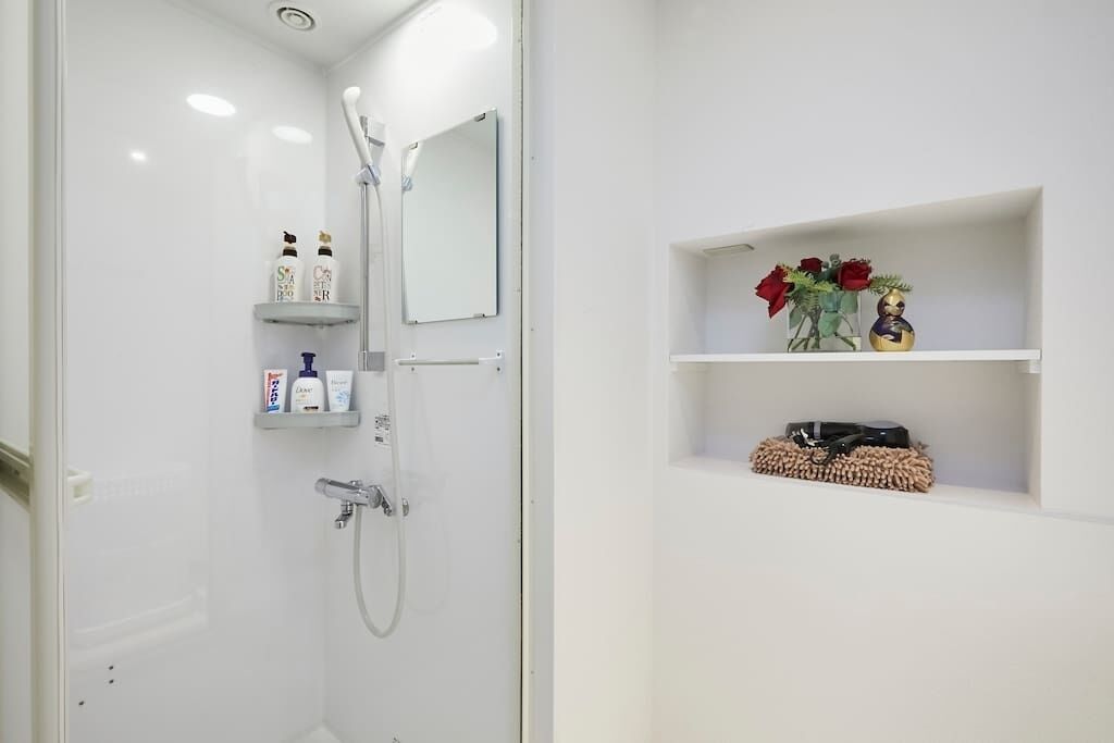 Ein modernes Badezimmer mit Dusche, Spiegel und Regalen mit Toilettenartikeln und Dekoration.