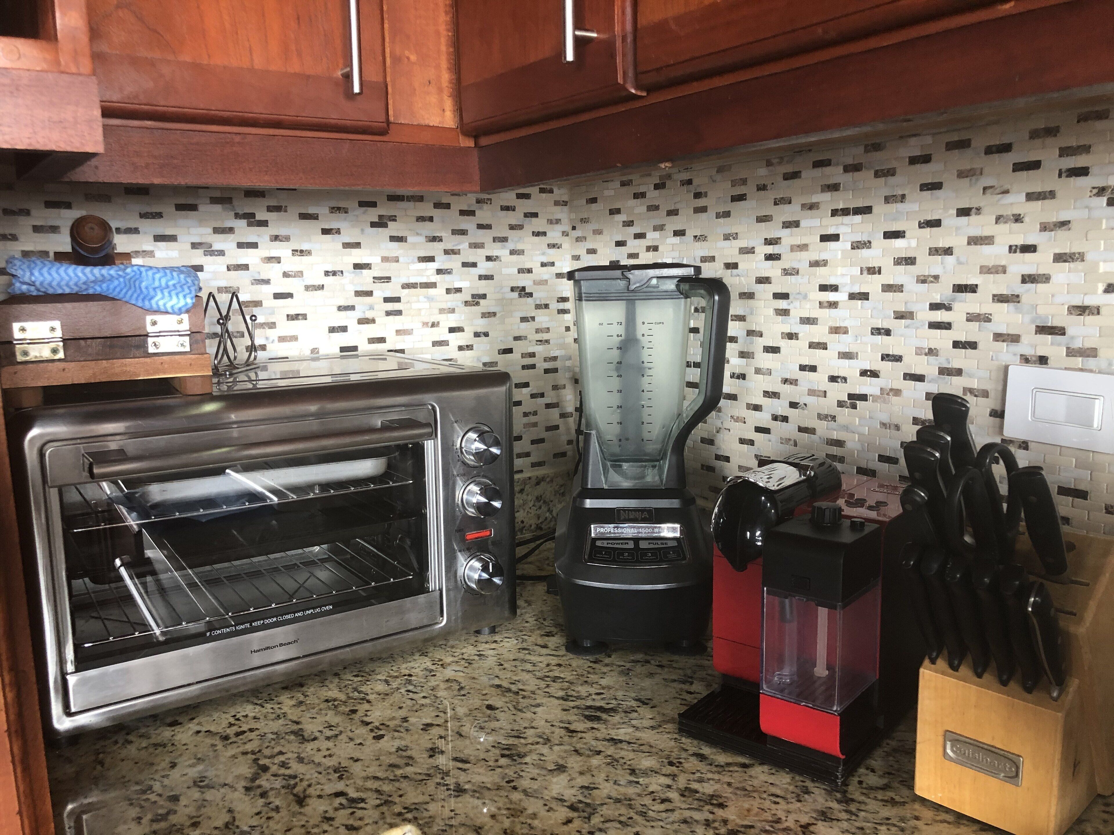 A kitchen with a built-in oven, a blender, and a knife block.