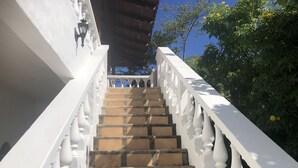 Eine Treppe mit weißen Geländern und Steinstufen, die zu einem Hauseingang führt.