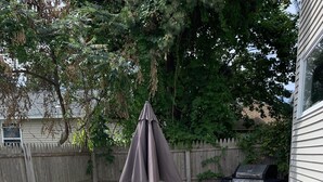 Une terrasse extérieure avec une table et des chaises, un barbecue et une clôture en bois.