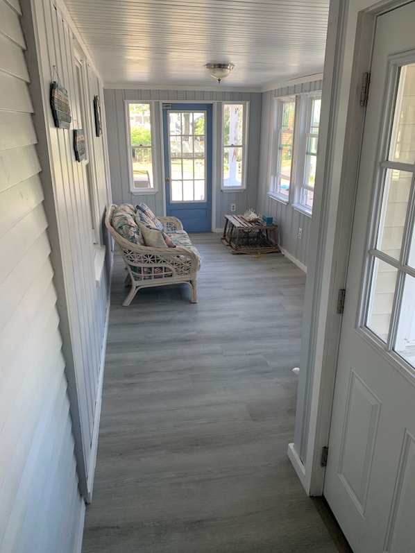 A covered porch with a wicker sofa, a small table, and a blue door.