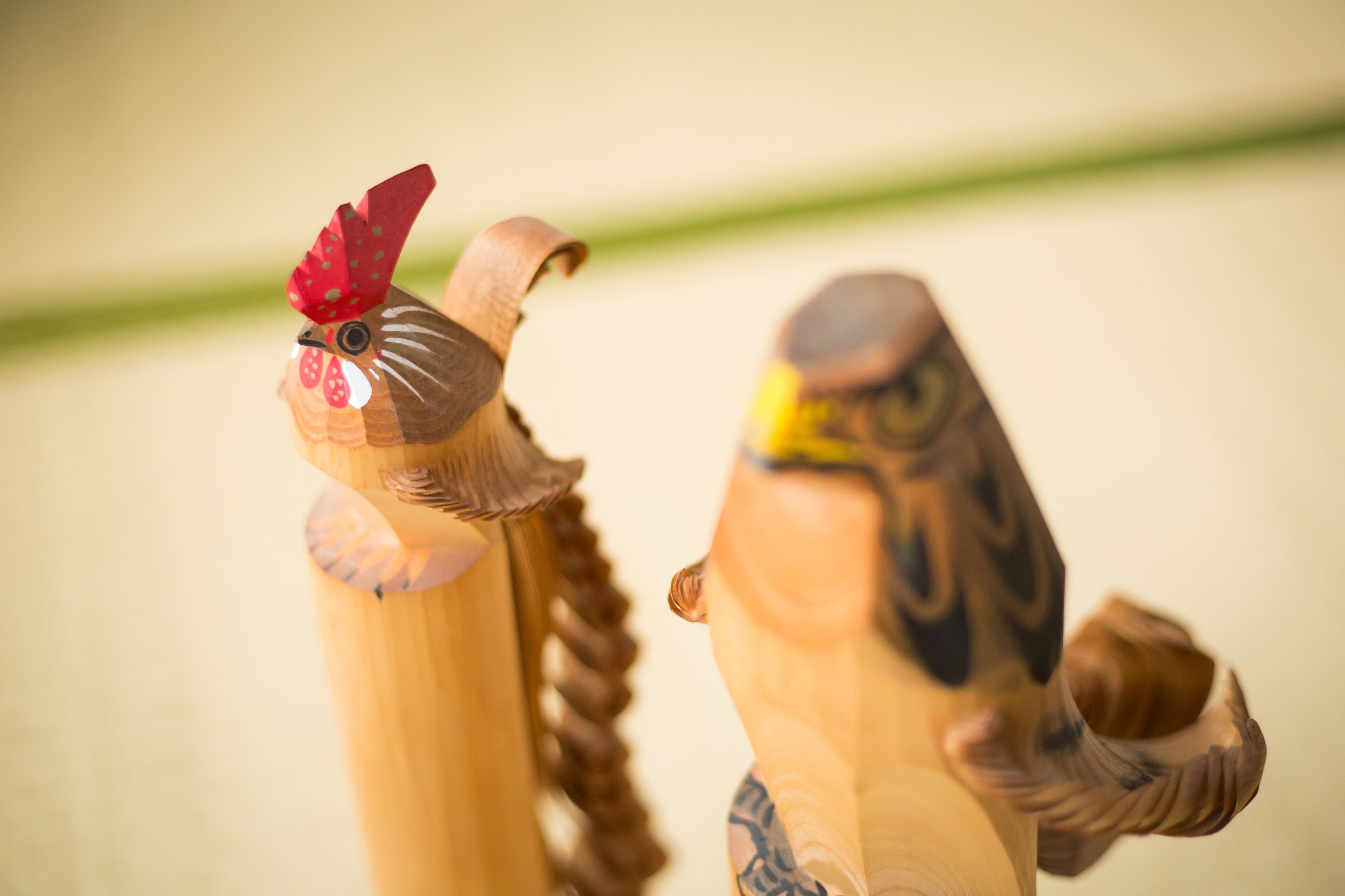 Two wooden sculptures of chickens with detailed carvings.