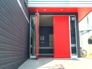 A modern building entrance with a red door and a glass entrance.
