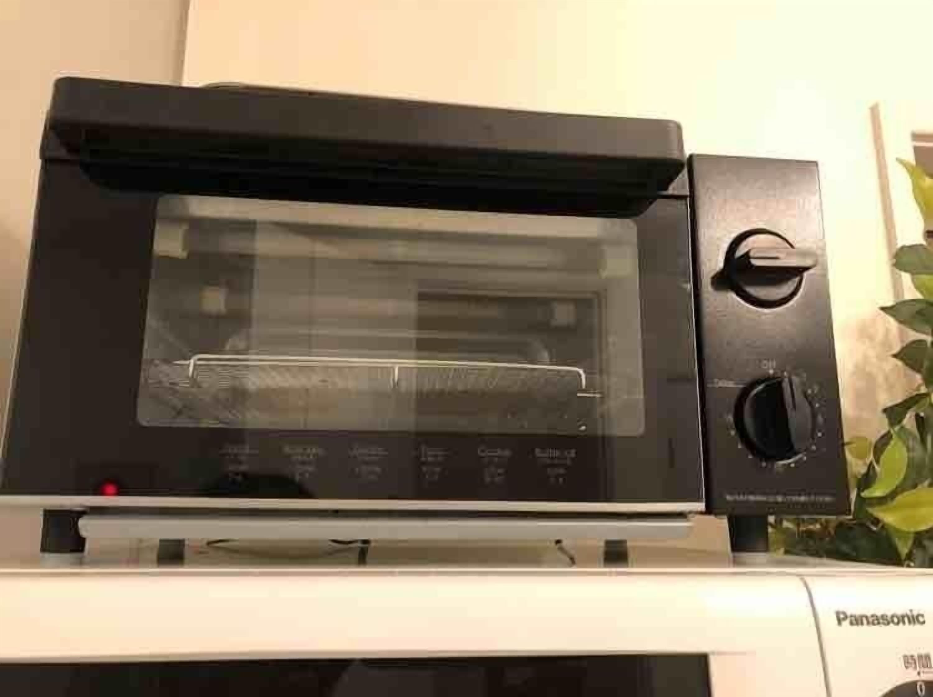 A black microwave oven with a digital display and a control knob on the right side.