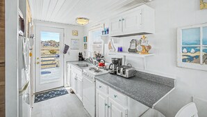 A compact kitchen with white cabinets, a stove, a sink, and a countertop.