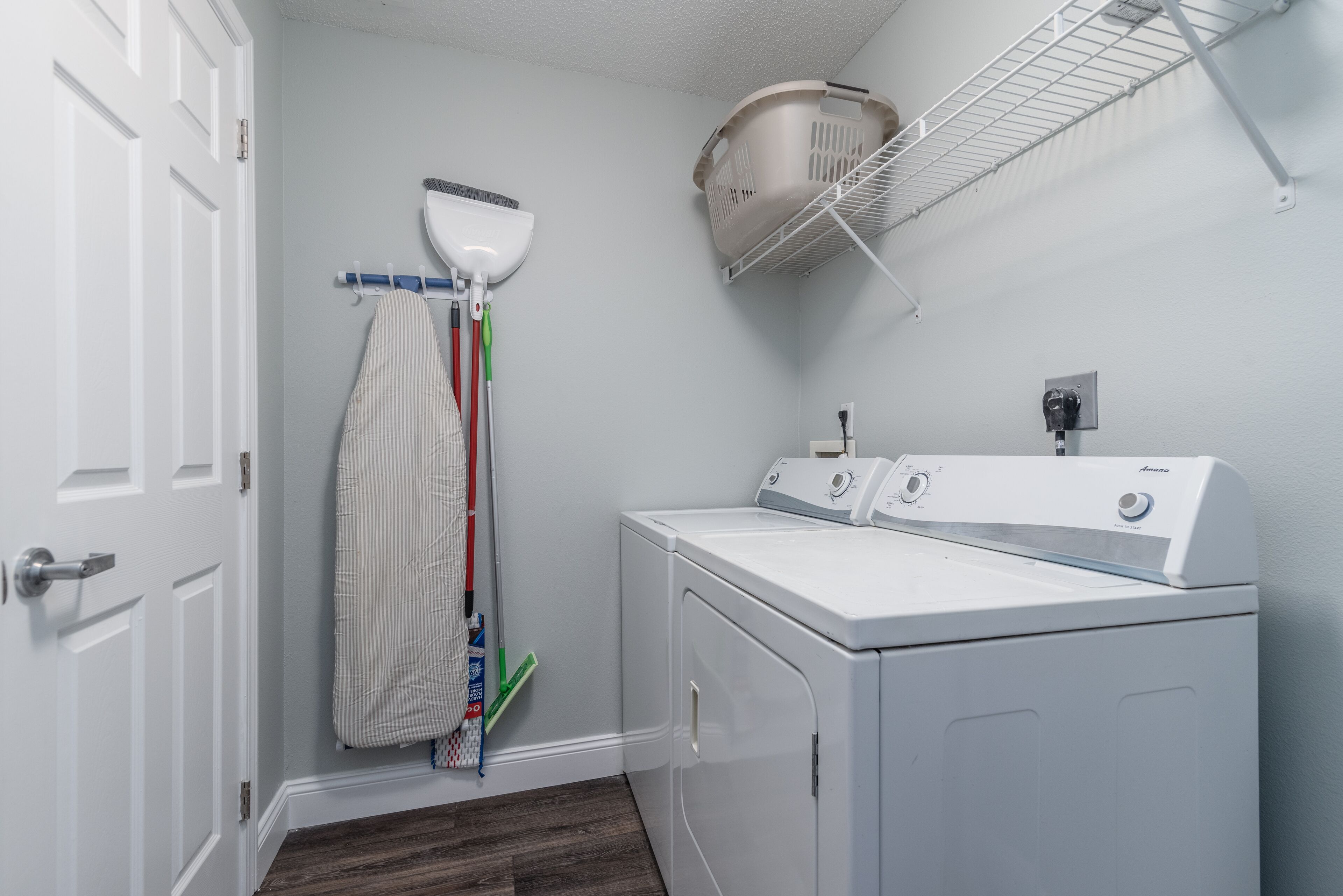 A laundry room with a washing machine, a drying rack, and a broom.