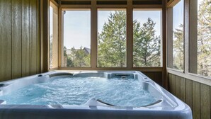 Una vasca idromassaggio con un pontile in legno e vista su alberi e case attraverso ampie finestre.
