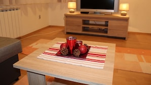Ein Wohnzimmer mit einer Holzunterhaltungsecke, einem Fernseher und einem Tisch mit einer rot-weiß gestreiften Tischdecke und dekorativen Accessoires.