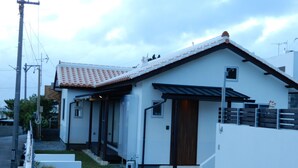 Ein modernes, zweistöckiges Haus mit Ziegeldach, Holztür und kleiner Veranda.