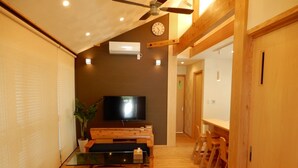 Ein Holzinnenraum mit Deckenventilator, Wanduhr und Flachbildfernseher.