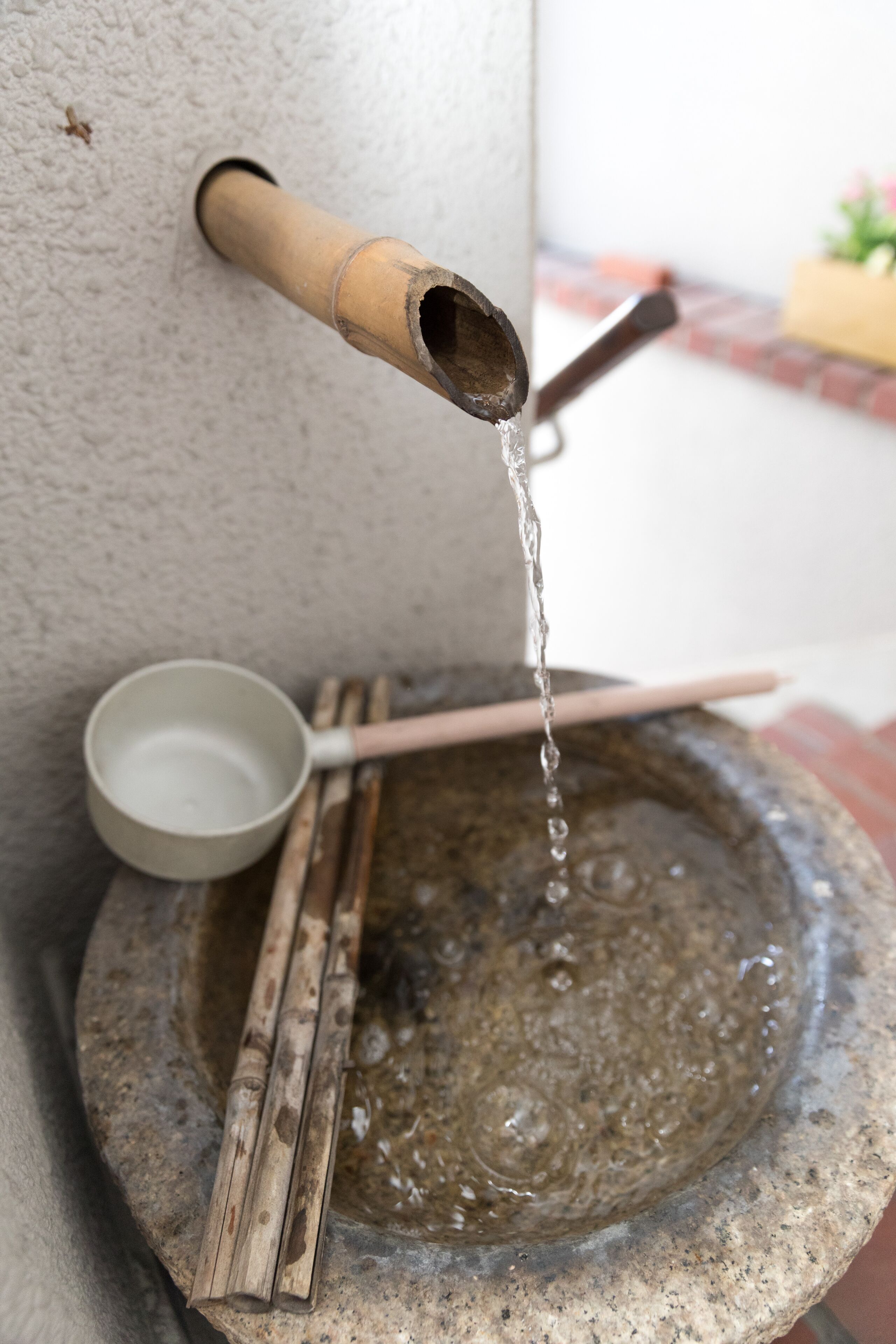 A stone basin with a bamboo spout and a wooden ladle.