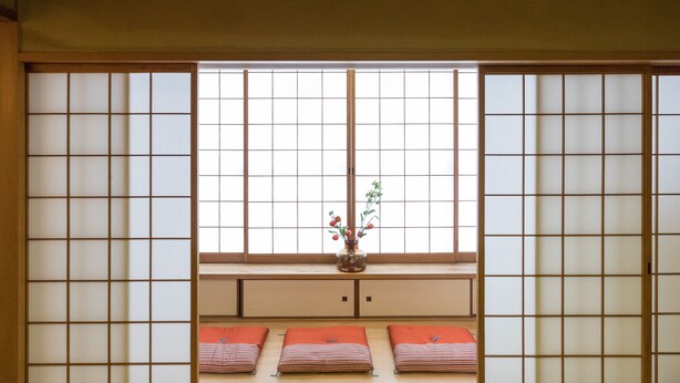 A traditional Japanese room with tatami flooring, sliding shoji doors, and a low table with cushions and a vase of flowers. - Large city villa near Osaka Castle 5 min (Ōsaka-shi)