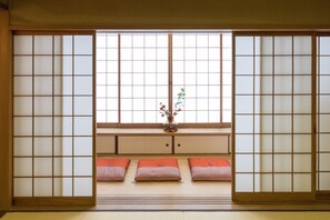 Een traditionele Japanse kamer met tatami vloeren, shoji schermen en een lage houten bank met kussens.