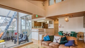 Een modern interieur met een glazen wand, een bank met decoratieve kussens, een eethoek en een keuken.