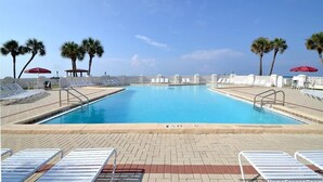 Una piscina con sillas de descanso y palmeras.