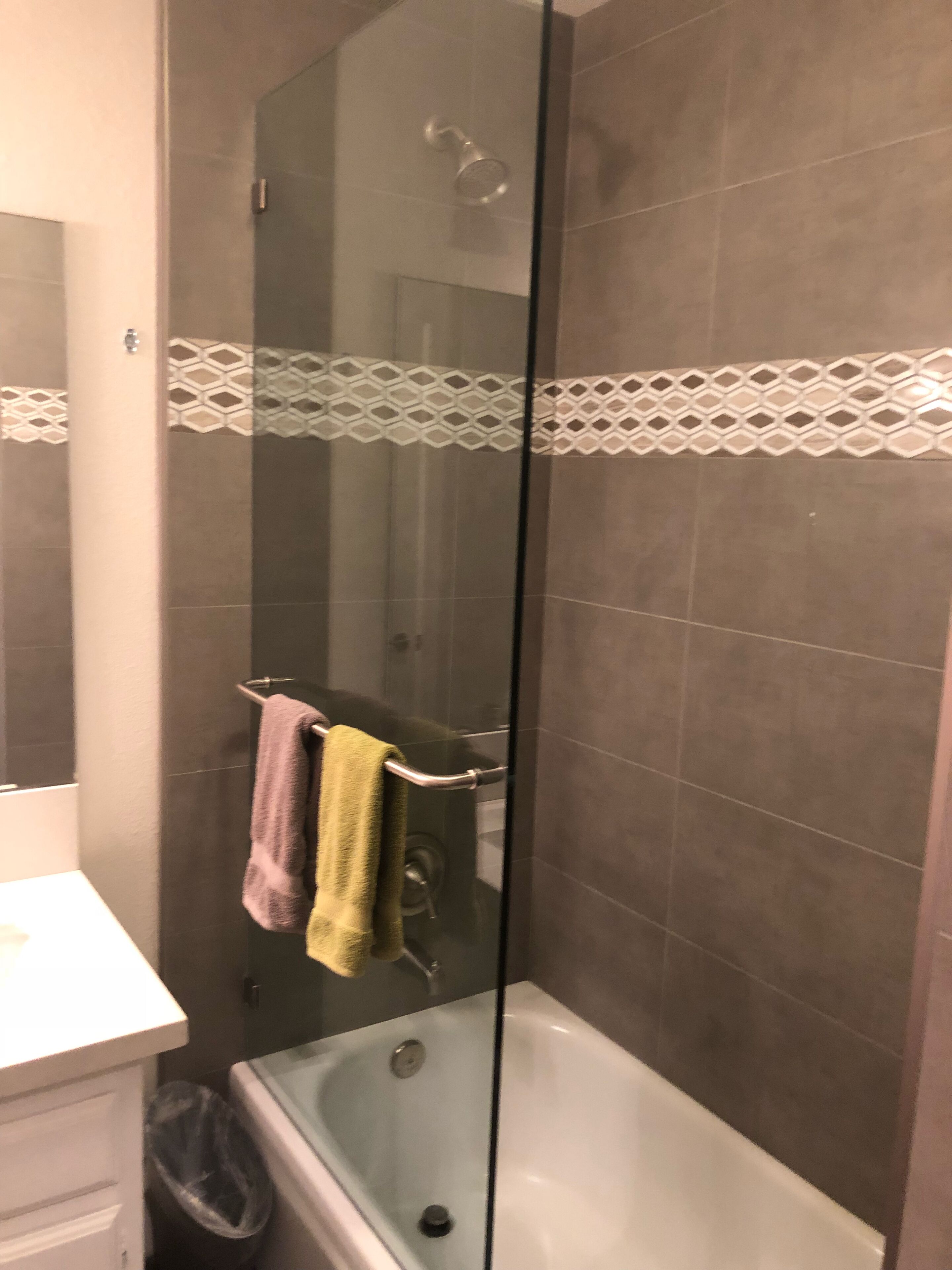 A bathroom with a glass shower enclosure, a bathtub, and a vanity with a mirror.