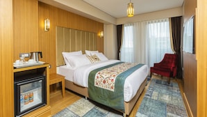 Habitación de hotel con cama, un refrigerador pequeño, una silla roja y un panel de pared de madera.