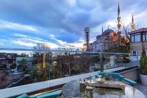A terrace with a table set for dining, overlooking a historic building with a prominent minaret. - Obelisk Hotel & Suites (Istanbul)