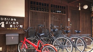 Eine Reihe von Fahrrädern vor einem Gebäude mit einer Holzfassade und einem Schild mit japanischen Schriftzeichen.