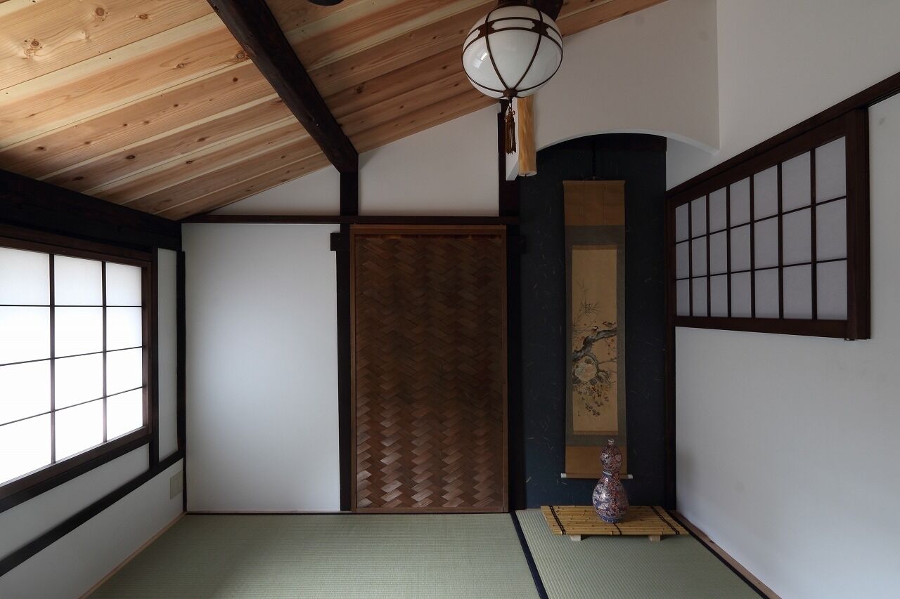 Una habitación japonesa tradicional con suelo de tatami, un puertas correderas shoji y un farol colgante.