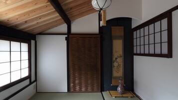 Una habitación japonesa tradicional con suelo de tatami, un puertas correderas shoji y un farol colgante.